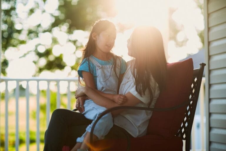 Mother and daughter sitting together on a porch at sunset, having a heartfelt conversation—capturing the beauty of biblical, grace-filled communication in everyday moments.