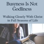 Pinterest graphic for a Christian blog post titled โBusyness Is Not Godliness: Walking Closely With Christ in Full Seasons of Lifeโ featuring a woman reading her Bible near a window.