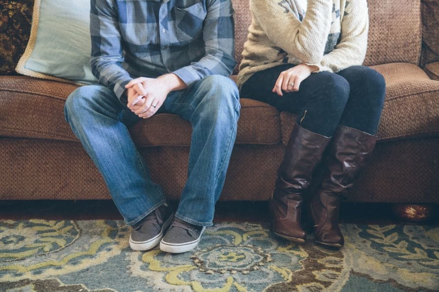 Christian husband and wife sitting apart on a couch, symbolizing common struggles in marriage and submission.