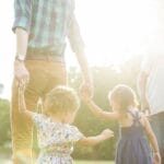 Young family walking hand in hand outdoors in soft sunlight, symbolizing unity, parenting, and making intentional choices guided by God’s Word.