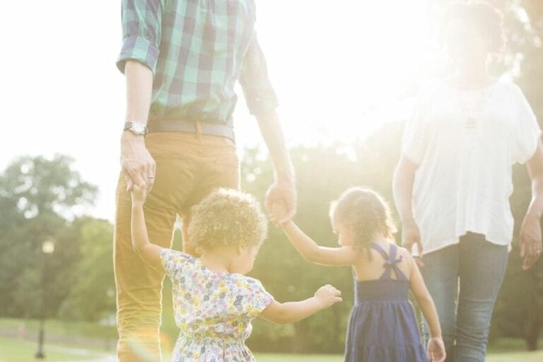 Young family walking hand in hand outdoors in soft sunlight, symbolizing unity, parenting, and making intentional choices guided by God’s Word.