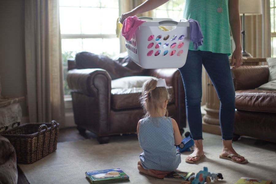 Christian homemaking daily life, mother doing laundry while child plays at home
