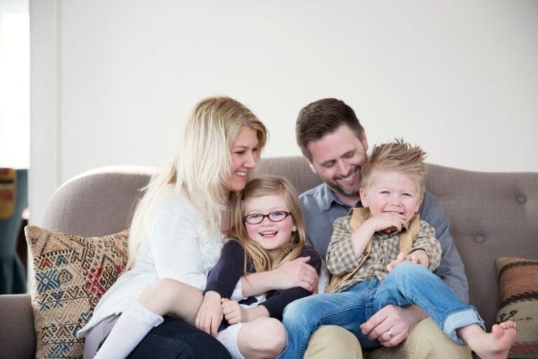 A joyful family gathered on the couch at home, reflecting the warmth, love, and everyday faithfulness of family life.