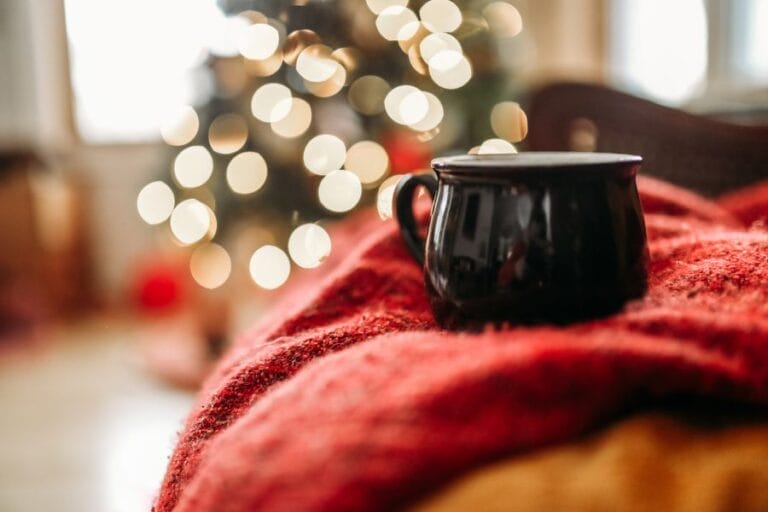 A quiet Christmas scene with a mug and glowing lights, symbolizing rest for weary hearts