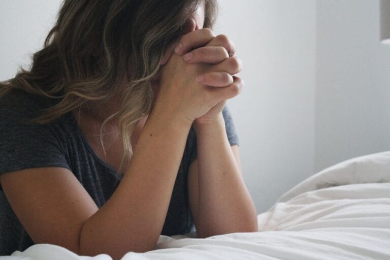 Woman praying with hands clasped, reflecting quiet humility and dependence on the Lord — a visual for being poor in spirit (Matthew 5:3).