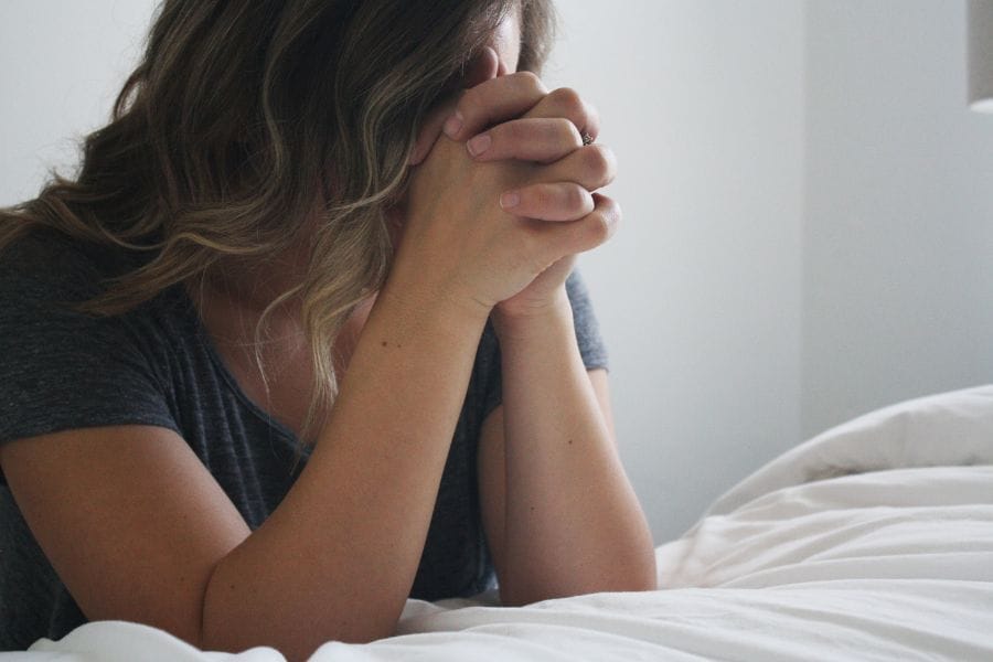 Woman praying with hands clasped, reflecting quiet humility and dependence on the Lord — a visual for being poor in spirit (Matthew 5:3).