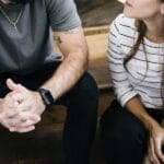 A Christian husband and wife sitting on wooden steps in serious conversation, reflecting on grace and biblical responses to sin in marriage.