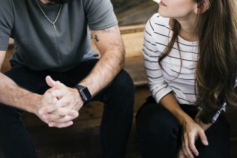 A Christian husband and wife sitting on wooden steps in serious conversation, reflecting on grace and biblical responses to sin in marriage.